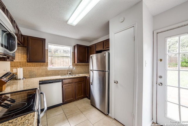 kitchen featuring a healthy amount of sunlight, light stone countertops, appliances with stainless steel finishes, and a sink