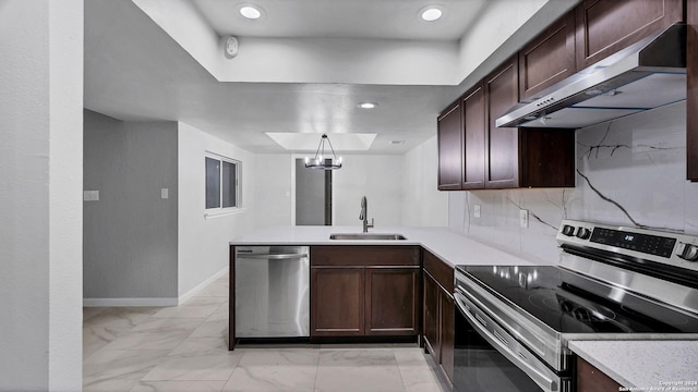 kitchen featuring kitchen peninsula, hanging light fixtures, stainless steel appliances, sink, and backsplash