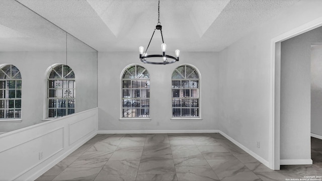 unfurnished dining area with a chandelier and a textured ceiling