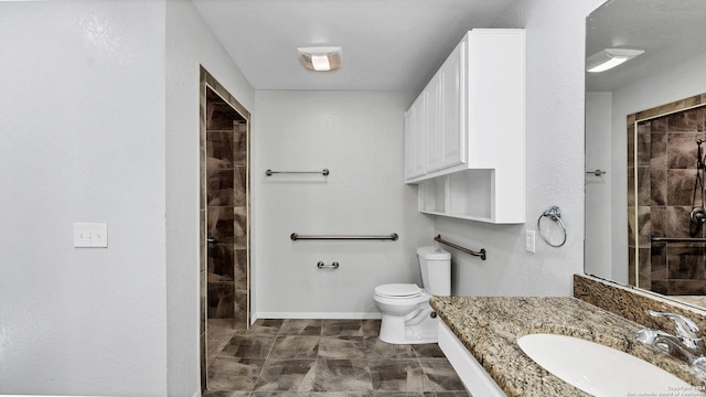 bathroom with tiled shower, vanity, and toilet