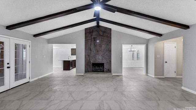 unfurnished living room with french doors, a high end fireplace, sink, vaulted ceiling with beams, and a textured ceiling