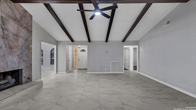 unfurnished living room with a fireplace, ceiling fan, a textured ceiling, and lofted ceiling with beams