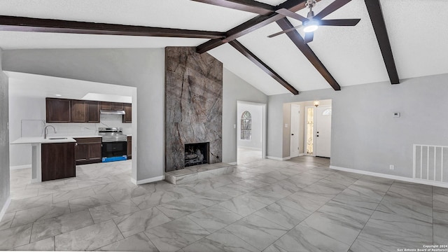 unfurnished living room featuring a high end fireplace, sink, ceiling fan, a textured ceiling, and beamed ceiling