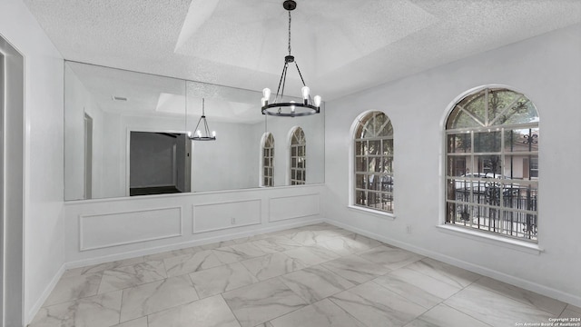 unfurnished dining area with a textured ceiling and a notable chandelier