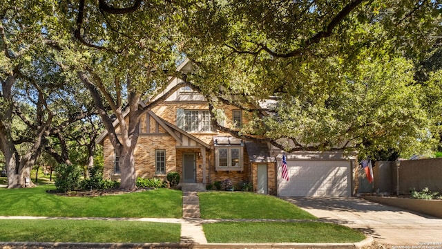 tudor home featuring an attached garage, brick siding, driveway, and a front lawn