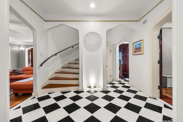 entryway with stairs, arched walkways, visible vents, and tile patterned floors