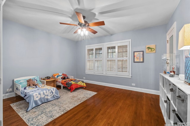 bedroom with dark wood-type flooring, a ceiling fan, and baseboards