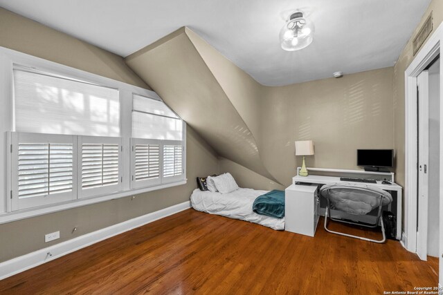 bedroom featuring lofted ceiling, baseboards, and wood finished floors