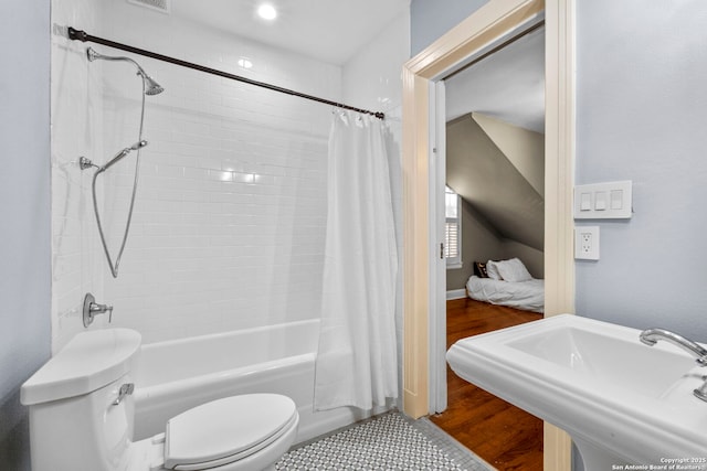 full bathroom featuring wood finished floors, shower / bath combo with shower curtain, a sink, and toilet