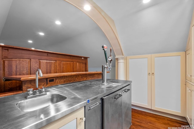 kitchen featuring arched walkways, dark wood-type flooring, a sink, vaulted ceiling, and stainless steel counters