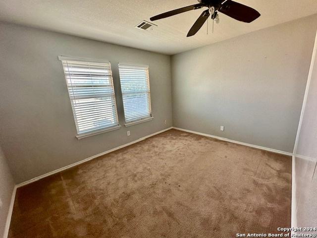 carpeted spare room featuring ceiling fan and a textured ceiling