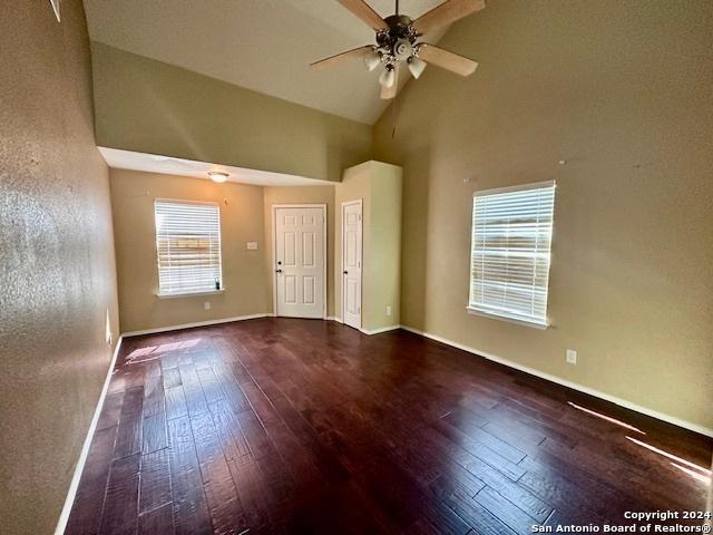 empty room featuring high vaulted ceiling, ceiling fan, and wood-type flooring