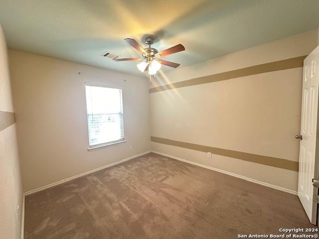 empty room with dark carpet and ceiling fan