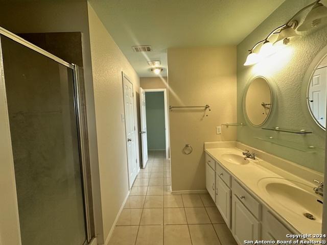 bathroom with tile patterned floors, vanity, and a shower with door