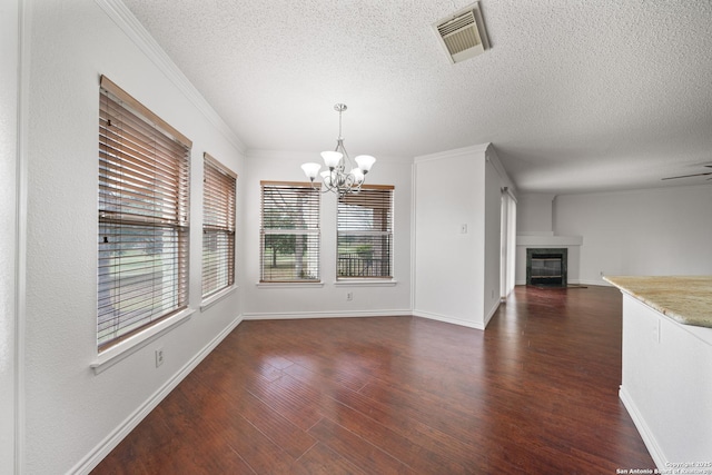 unfurnished dining area with a textured ceiling, ornamental molding, a chandelier, and dark hardwood / wood-style floors