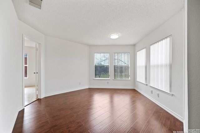 unfurnished room featuring dark wood-type flooring and a textured ceiling