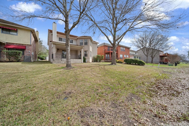 rear view of property with central AC unit and a lawn