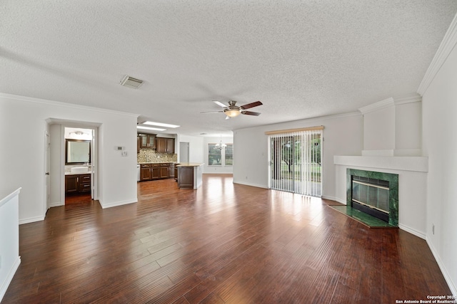 unfurnished living room featuring a fireplace, crown molding, dark hardwood / wood-style floors, and ceiling fan with notable chandelier