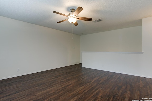 spare room with a textured ceiling, visible vents, baseboards, a ceiling fan, and dark wood finished floors