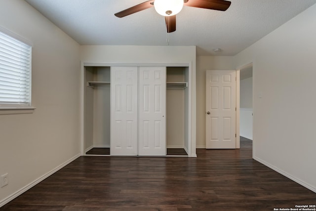 unfurnished bedroom featuring dark wood-style flooring, a closet, a ceiling fan, and baseboards