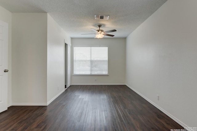 spare room featuring dark wood-style flooring, visible vents, a ceiling fan, a textured ceiling, and baseboards