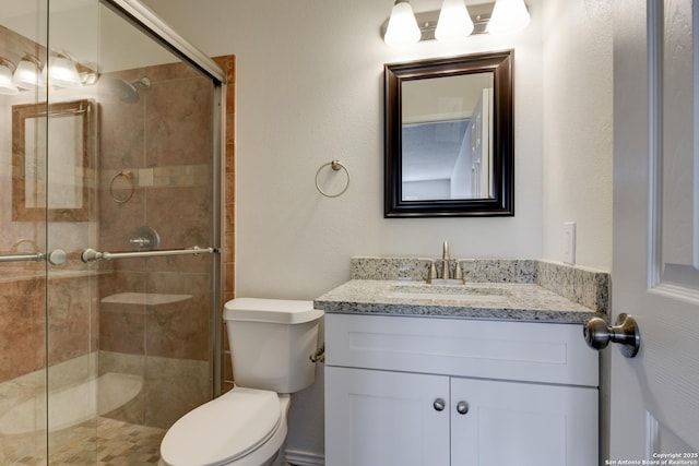 bathroom with a tile shower, vanity, and toilet