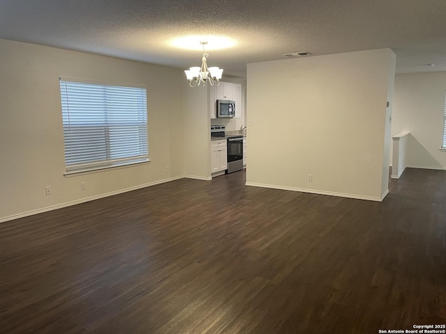 interior space with dark wood-style floors, baseboards, visible vents, and a textured ceiling