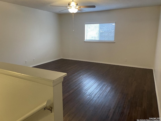 unfurnished room with a textured ceiling, dark wood-type flooring, a ceiling fan, and baseboards