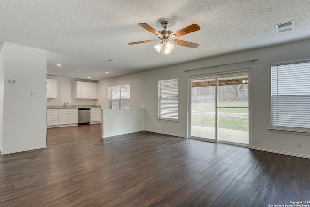 unfurnished living room featuring dark wood-style floors, baseboards, and a textured ceiling