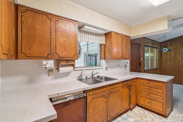 kitchen featuring brown cabinets, dishwashing machine, light countertops, and a sink