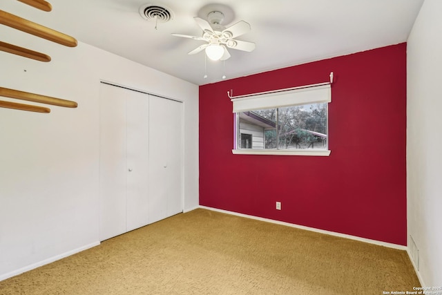 unfurnished bedroom featuring carpet flooring, visible vents, baseboards, a ceiling fan, and a closet