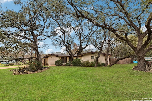 view of front facade featuring brick siding, fence, and a front lawn