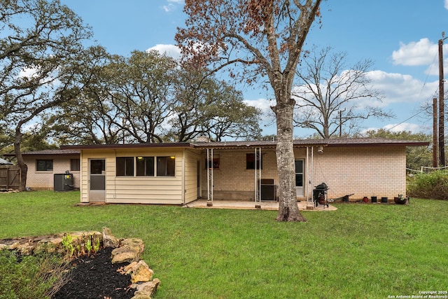 view of front of property with a front lawn, a patio area, brick siding, and central air condition unit