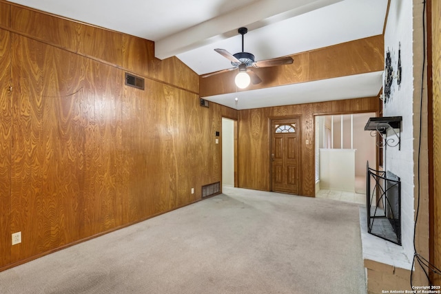 unfurnished room with light carpet, visible vents, lofted ceiling with beams, ceiling fan, and wood walls