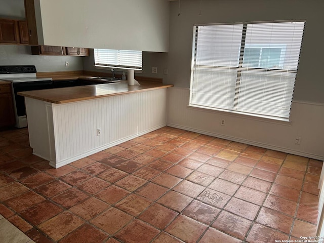 kitchen featuring sink, electric range oven, and kitchen peninsula