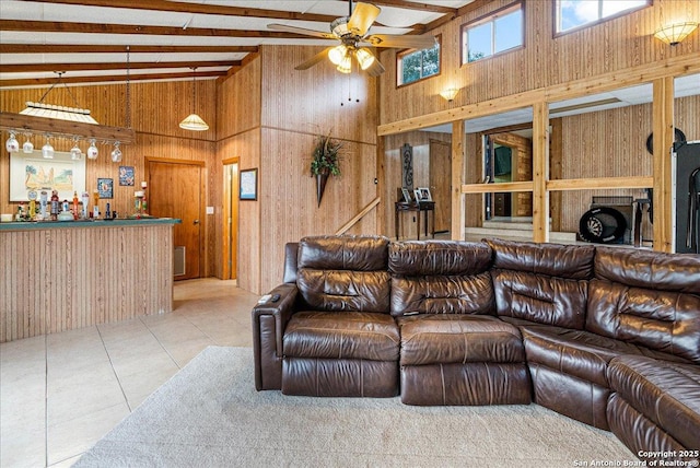 living room featuring vaulted ceiling with beams, wooden walls, ceiling fan, bar, and light tile patterned floors