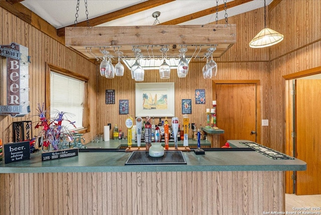 kitchen with beam ceiling, hanging light fixtures, high vaulted ceiling, wood walls, and kitchen peninsula