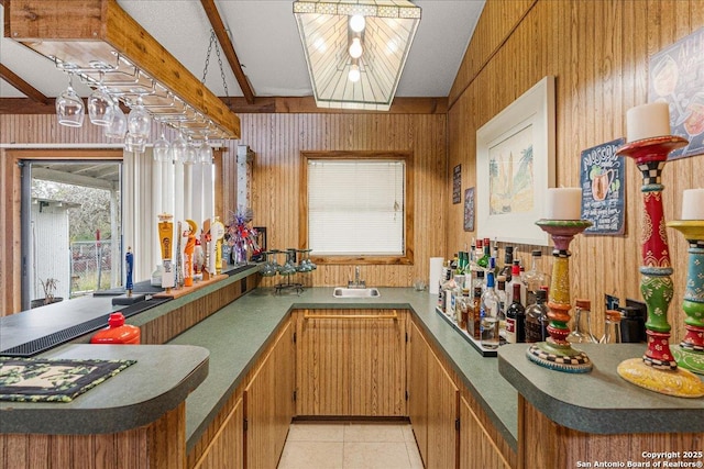 kitchen featuring sink, beam ceiling, wood walls, and light tile patterned floors