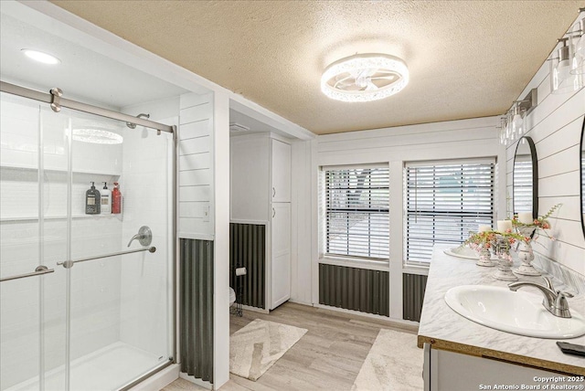 bathroom featuring hardwood / wood-style flooring, vanity, a shower with shower door, and a textured ceiling