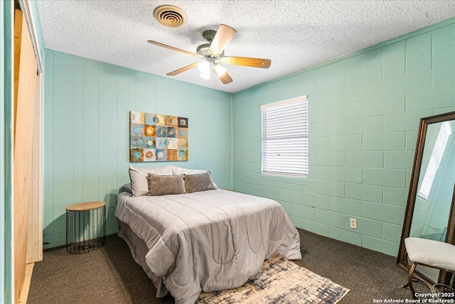 bedroom featuring ceiling fan, dark colored carpet, and a textured ceiling