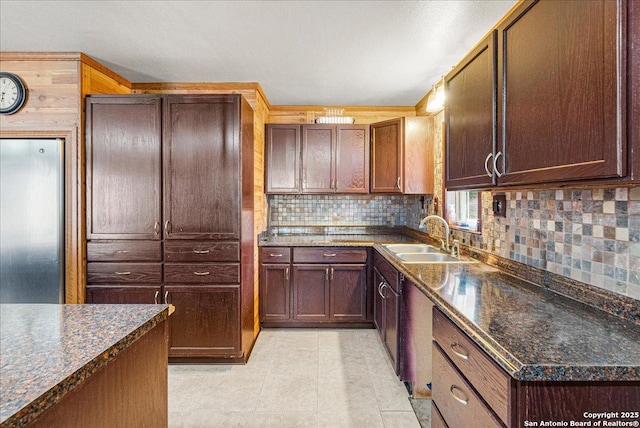 kitchen with sink, backsplash, dark stone countertops, and light tile patterned flooring