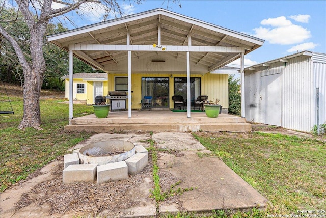 back of house with a patio, a yard, and a fire pit