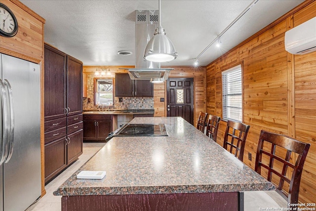 kitchen featuring a center island, wood walls, and stainless steel fridge