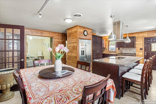 dining area featuring a textured ceiling and wooden walls