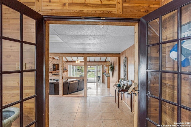 hall with light tile patterned floors and wood walls