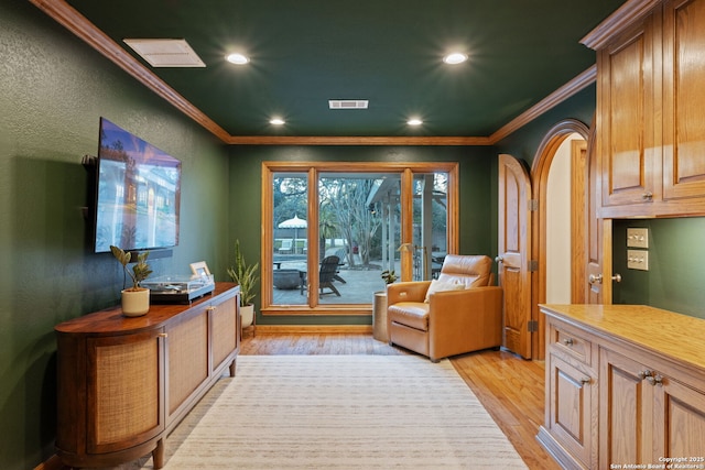 living area featuring light wood-type flooring and ornamental molding