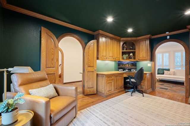 office with crown molding, light hardwood / wood-style flooring, and built in desk