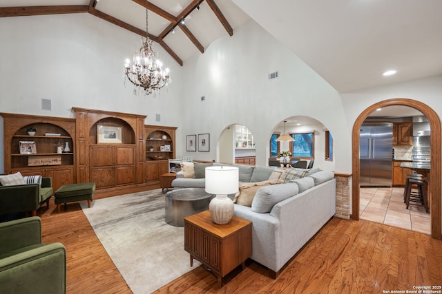 living room featuring light hardwood / wood-style flooring, lofted ceiling with beams, and an inviting chandelier