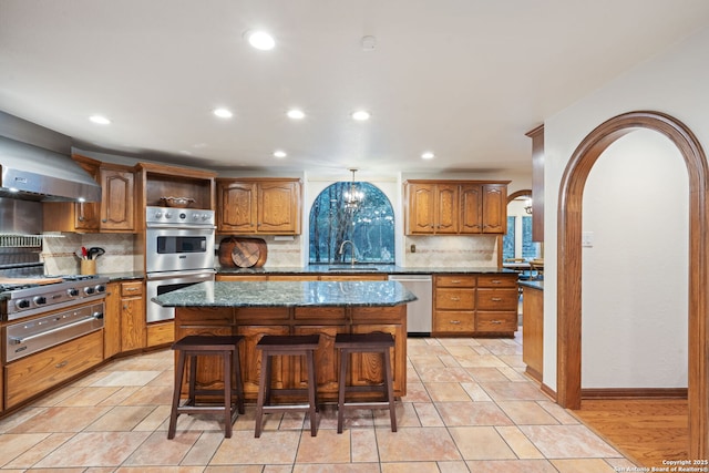 kitchen with sink, appliances with stainless steel finishes, a kitchen island, and a breakfast bar area