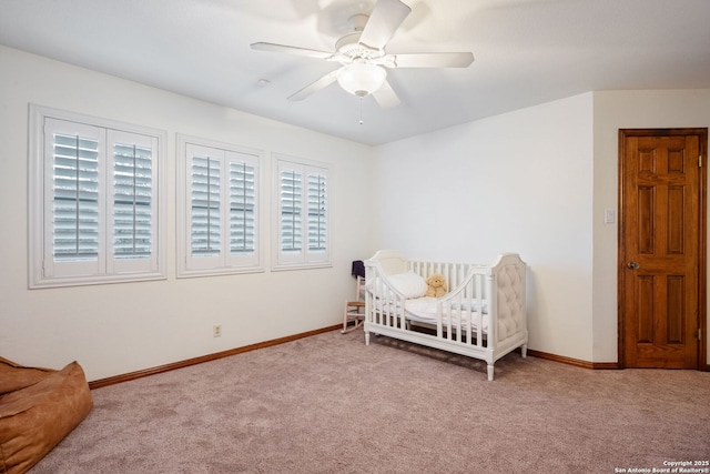 bedroom with ceiling fan, a crib, and light carpet